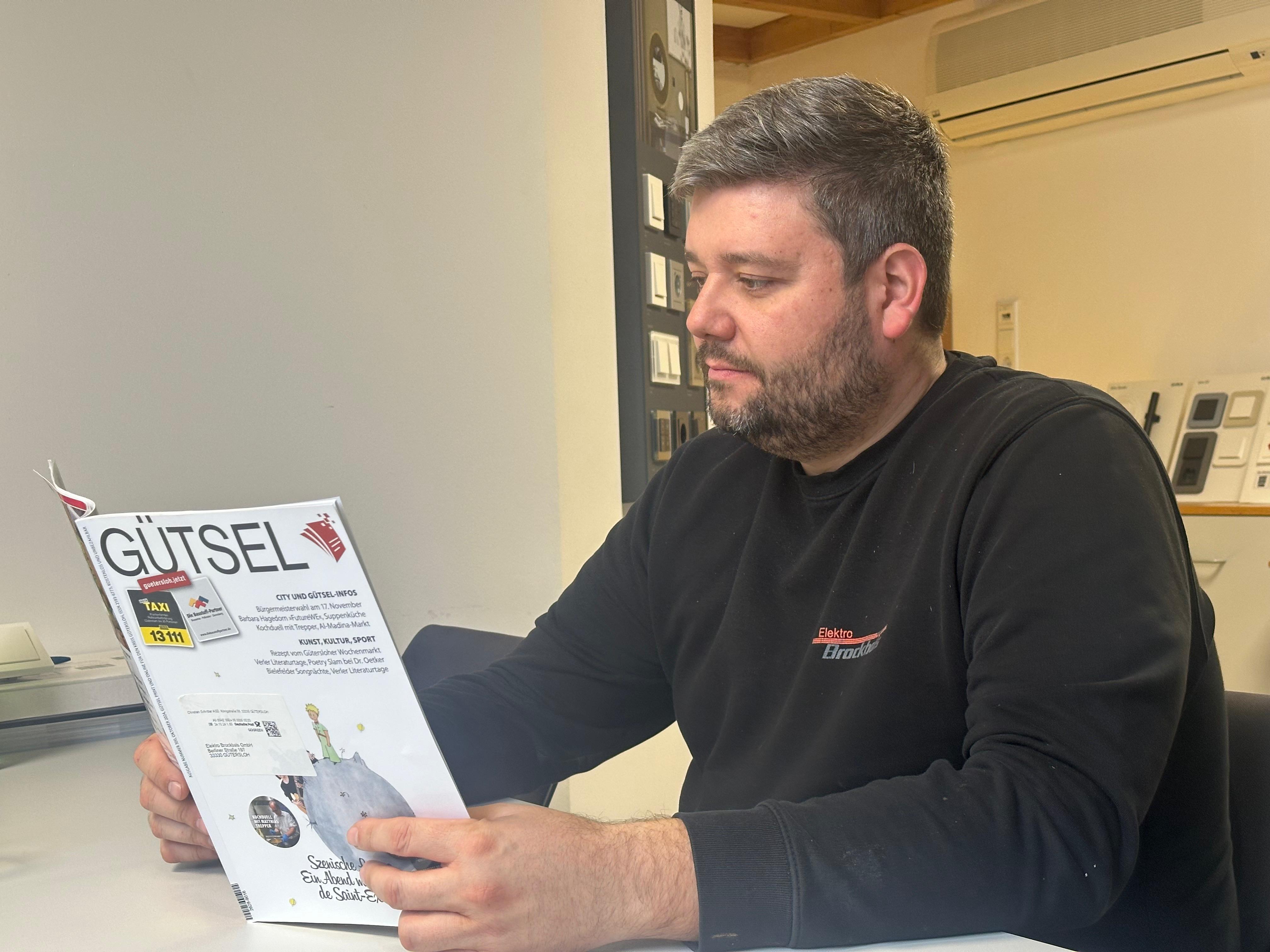 Geschäftsführer Christian Hinzmann sitzt am Schreibtisch und liest in der Zeitschrift Gütsel