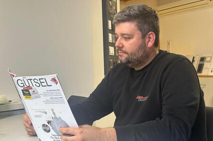 Geschäftsführer Christian Hinzmann sitzt am Schreibtisch und liest in der Zeitschrift Gütsel