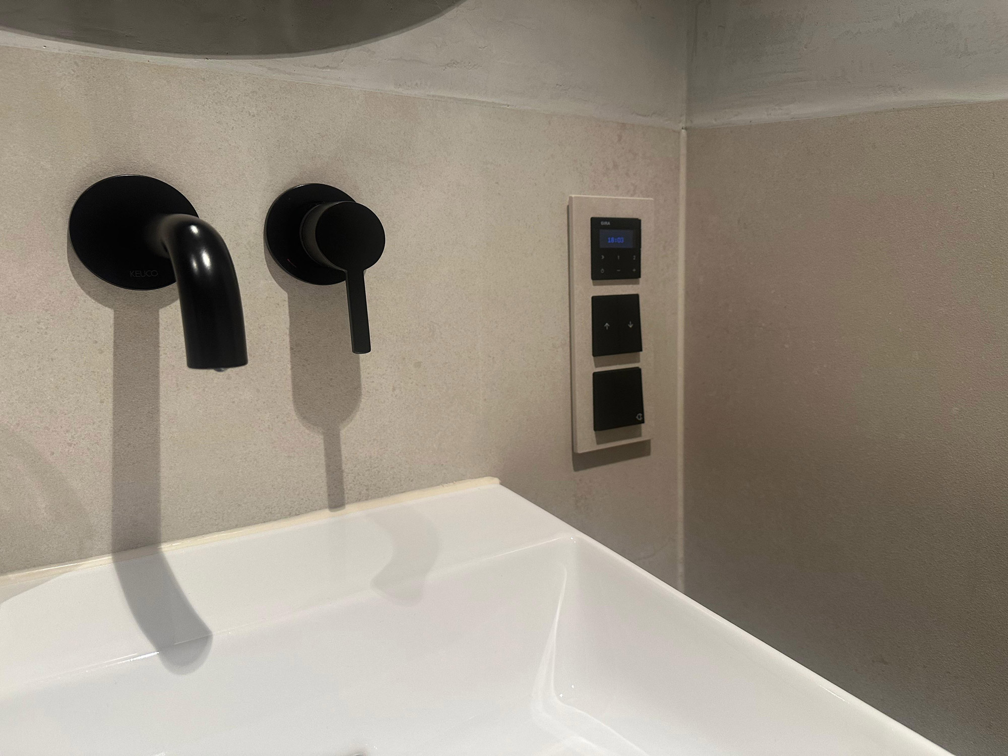 Eine Badezimmerarmatur auf der die Schalter in Wandoptik eingefasst sind