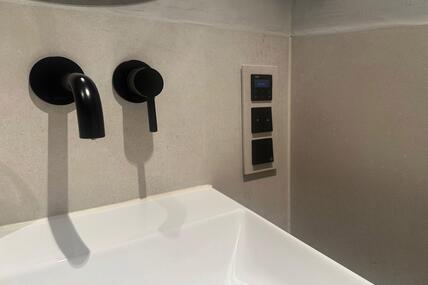 Eine Badezimmerarmatur auf der die Schalter in Wandoptik eingefasst sind
