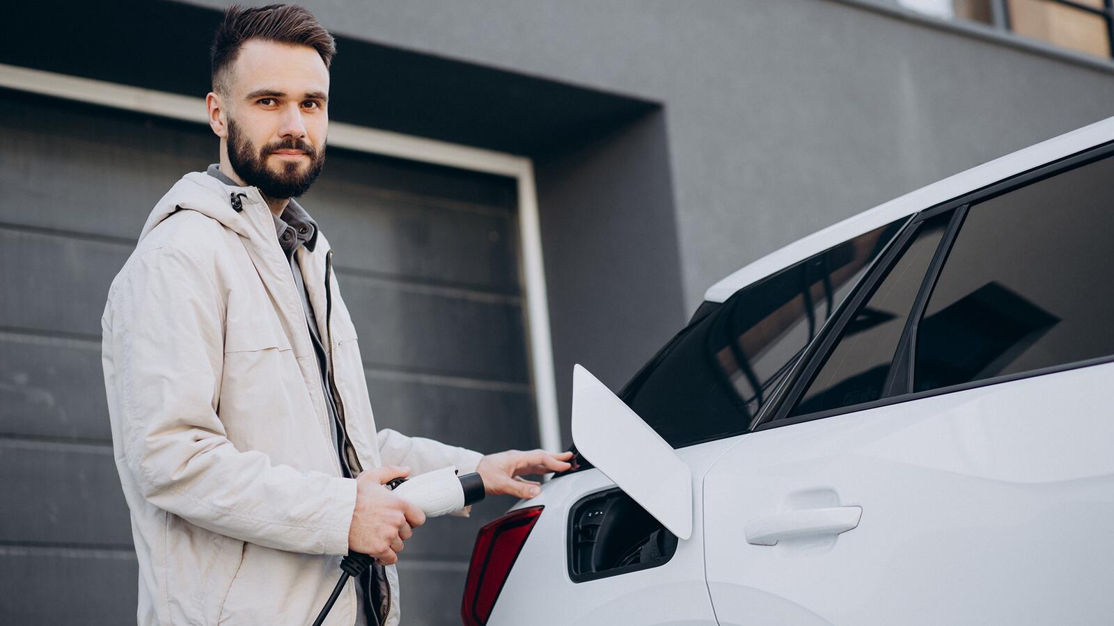 Mann lädt Elektroauto am Haus auf